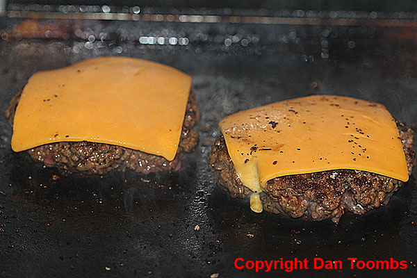 Topping the burgers with cheese.