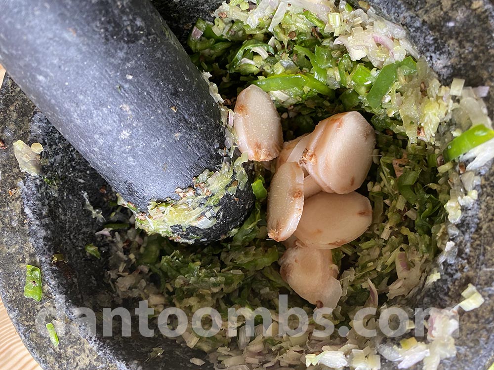 Pounding galangal into green curry paste