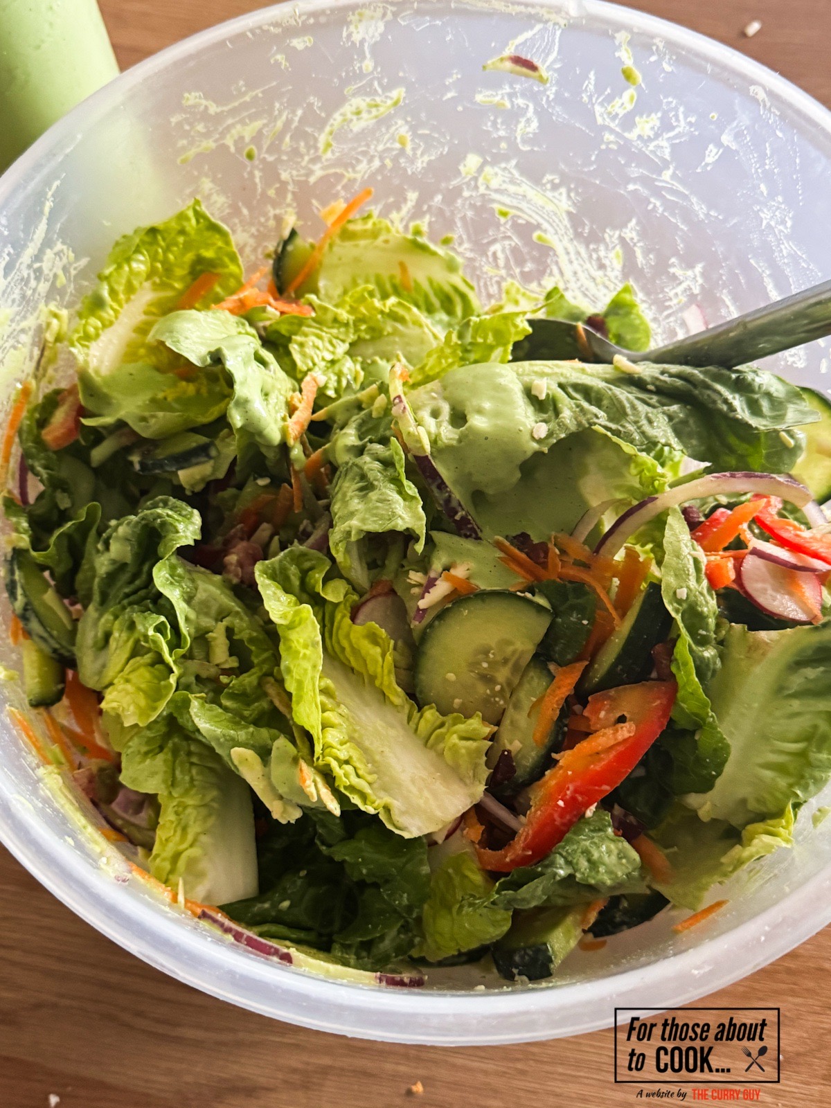 Green Goddess dressing being mixed into a green salad.