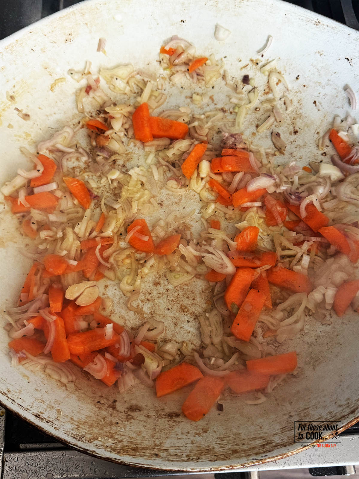 Adding the chopped shallots and carrots to the pan to fry for a few minutes.
