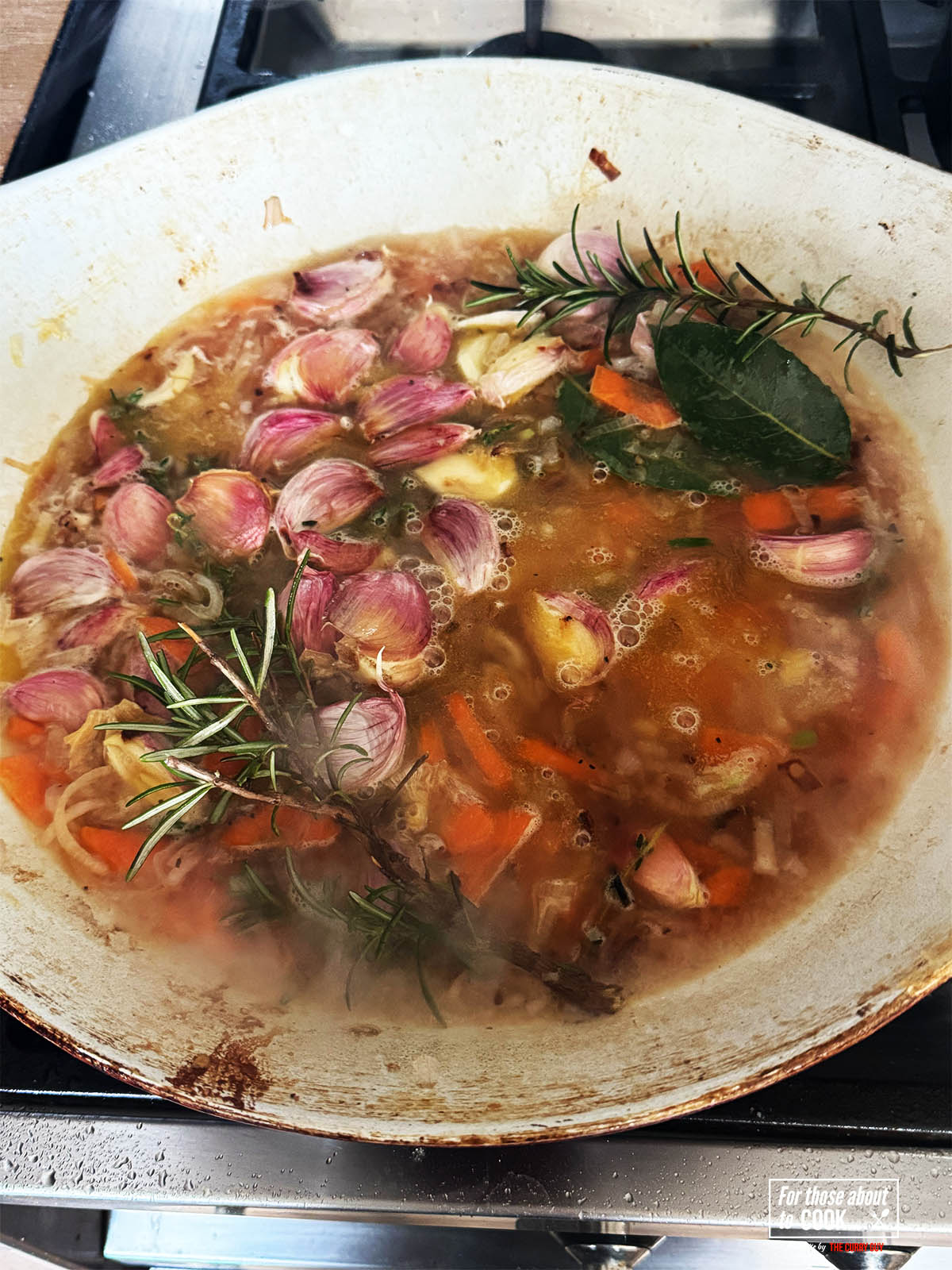 Covering the vegetables, herbs and garlic with the wine and stock to bring to a simmer.