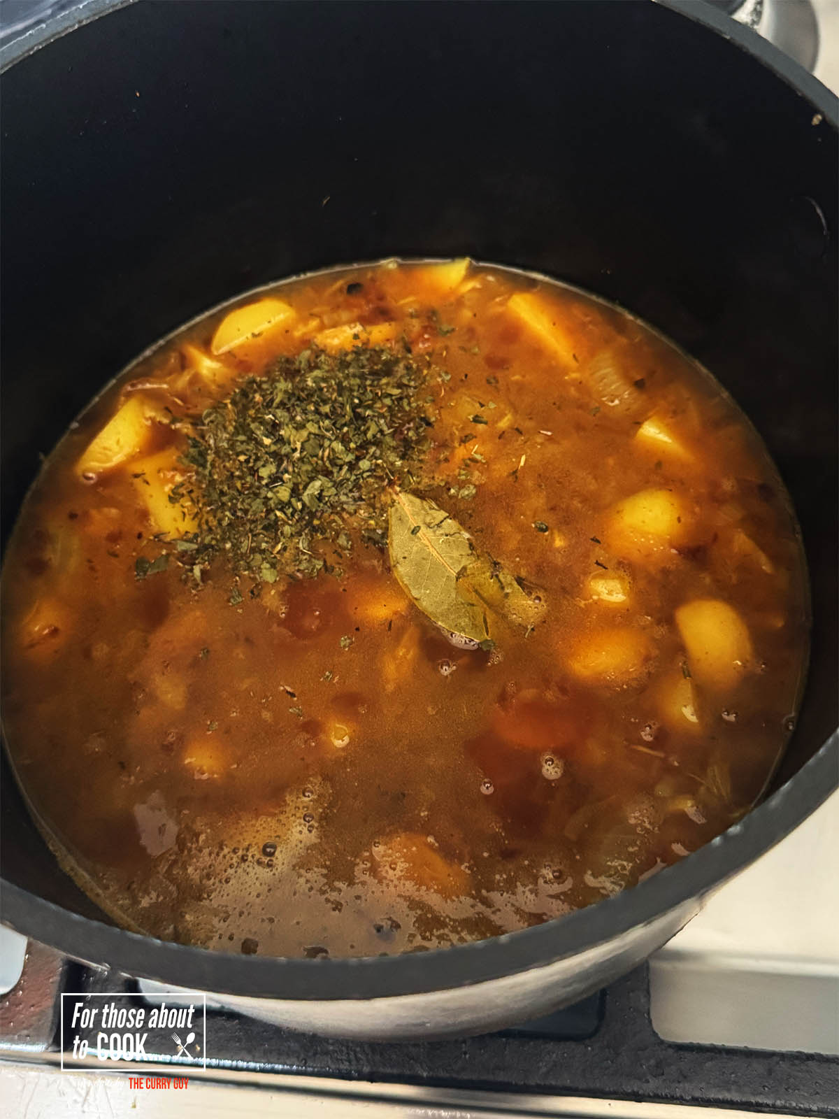 Adding the wine, stock and herbs to the pot.