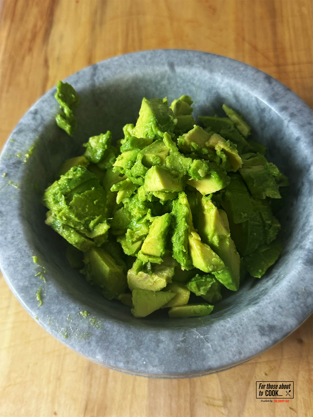 Placing the cut up avocado in a pestle and mortar.