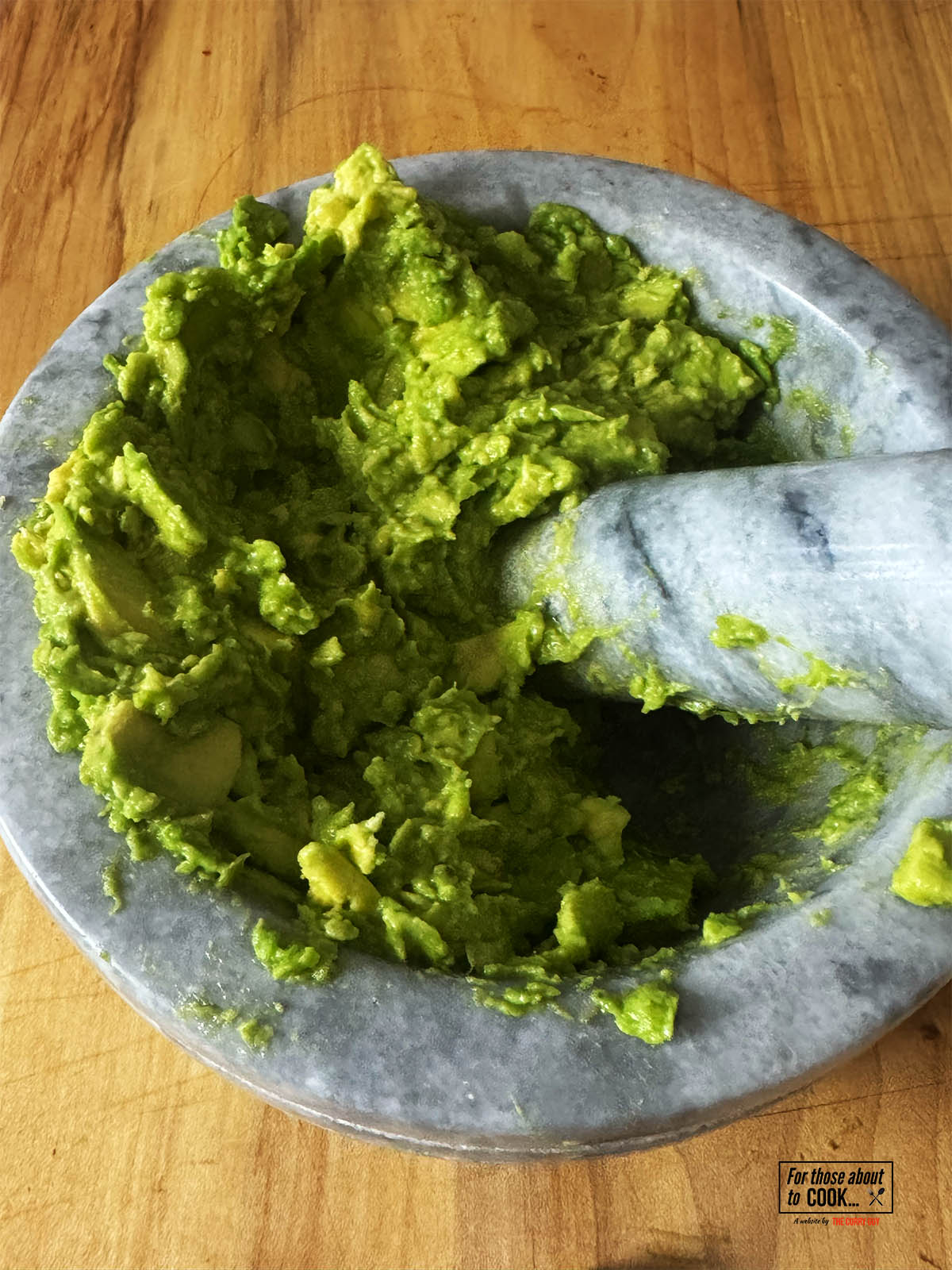 Pounding the avocado in a pestle and mortar.