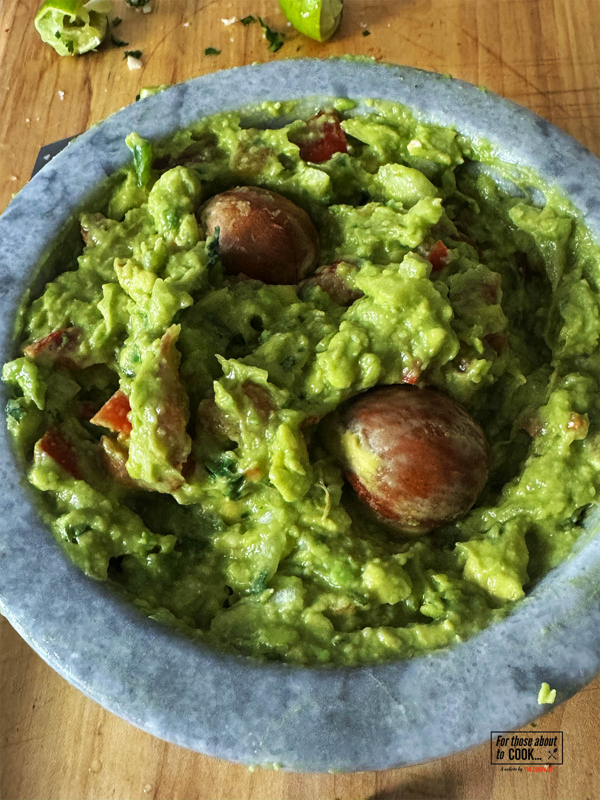 Seasoning with salt to taste and adding the pits to the guacamole to help preserve the color.