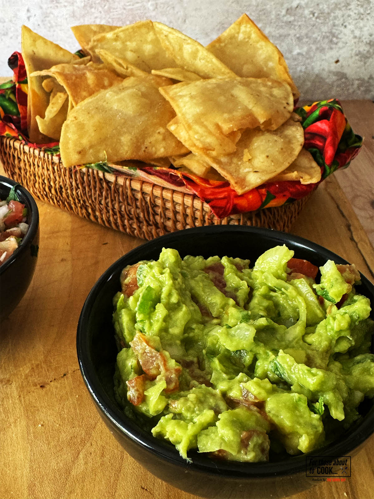Serving the guacamole in a bowl next to corn chips.