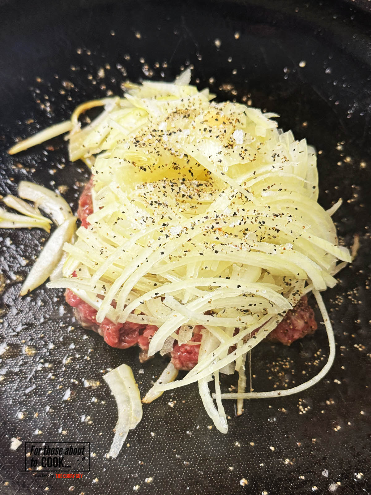 Sliced onions added to the top of burger patty