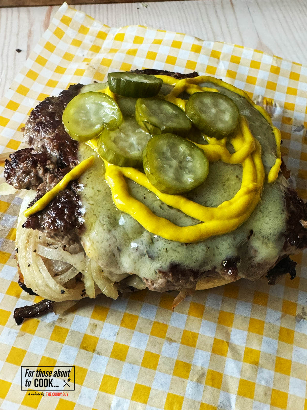 Bottom bun topped with burger. mustard and pickles