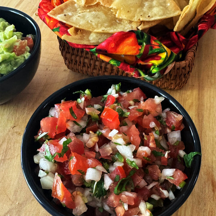 Pico de gallo in a serving bowl next to homemade corn chips.