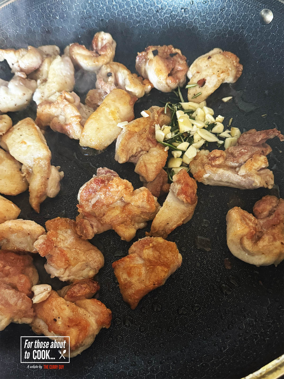 Turning the chicken and adding the garlic and rosemary.