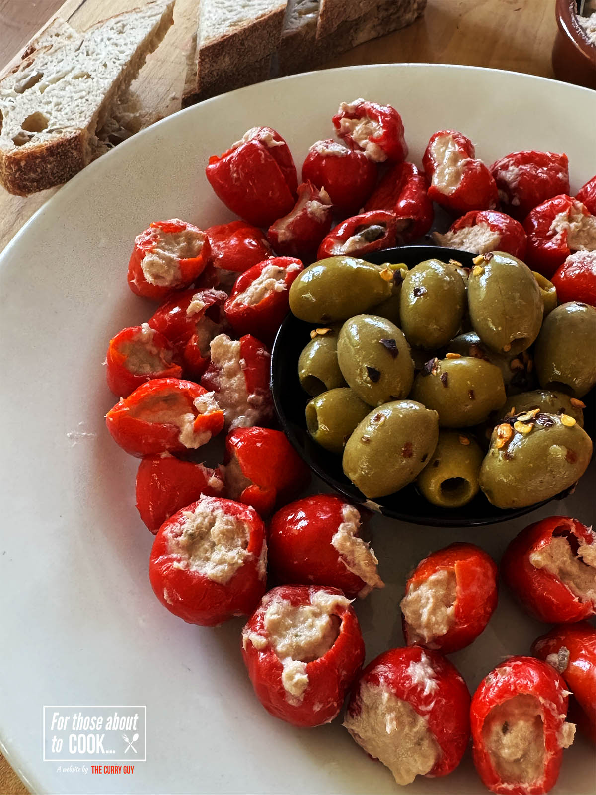 The tuna stuffed peppers on a serving plate with olives.