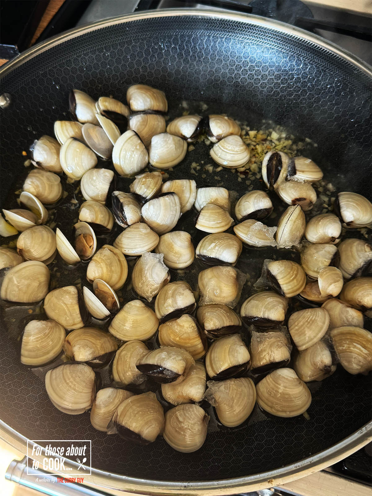 Adding the wine and clams to the pot.