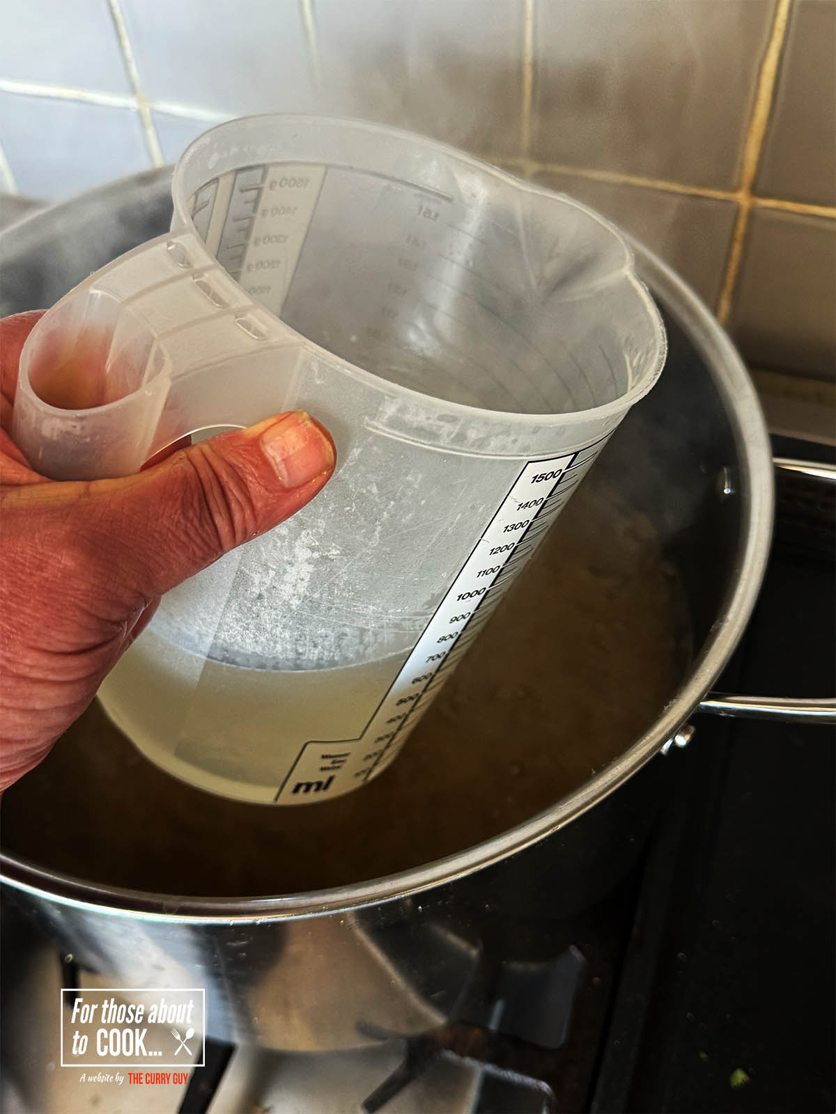Scooping up some of the cooking water before draining the pasta.