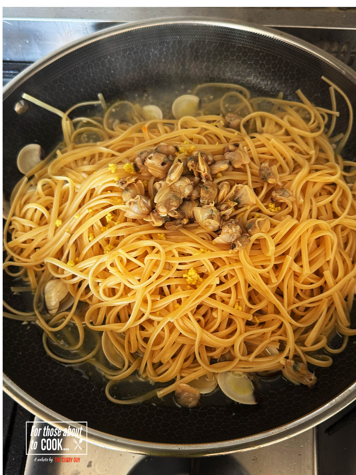 Adding the drained pasta, lemon zest and the clams that are out of the shell.