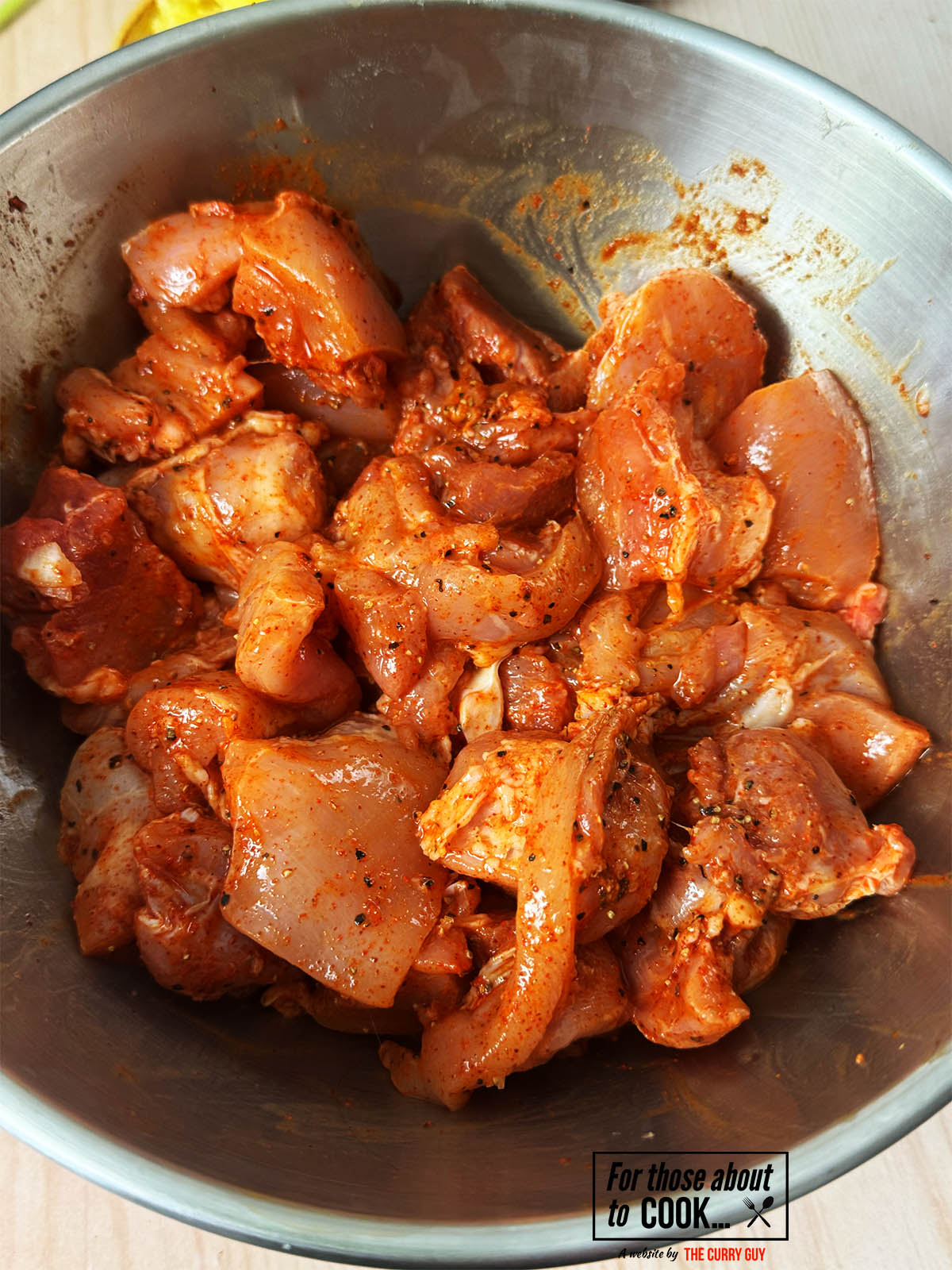 The chicken pieces marinating in a bowl.