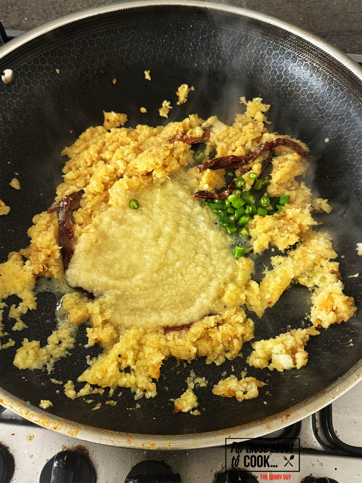 Adding the blended onions, garlic and ginger paste and chillies to the pan.