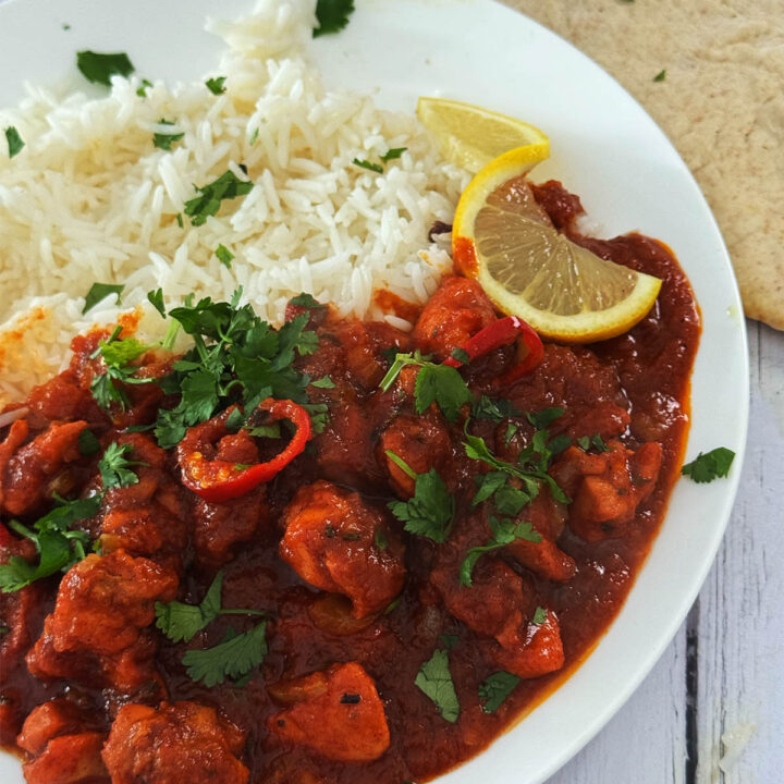 30 Minute Chicken Pathia on a serving plate next to rice and naans.