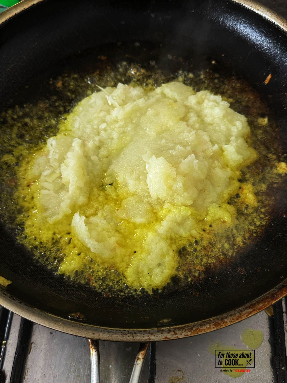 Adding the blended onion paste to ghee in a hot pan.