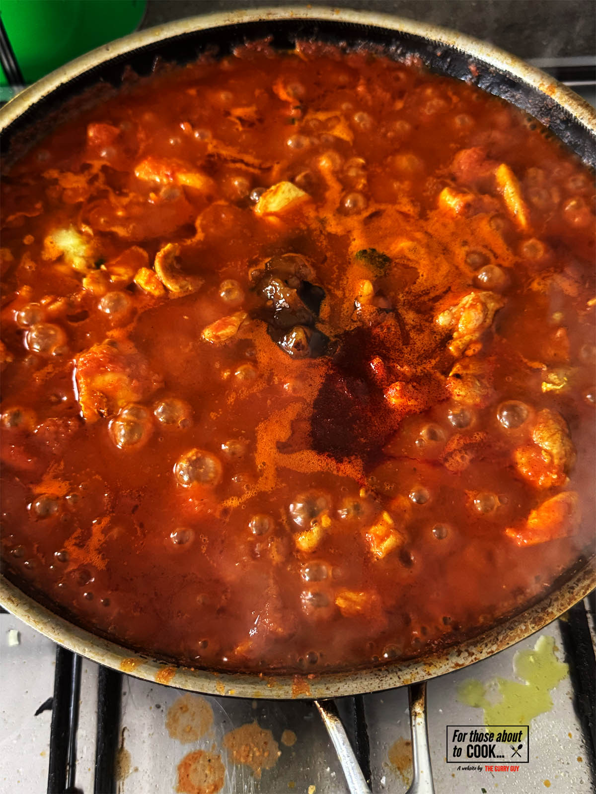 Adding the tamarind concentrate, mango chutney and optional red food colouring to the pan.
