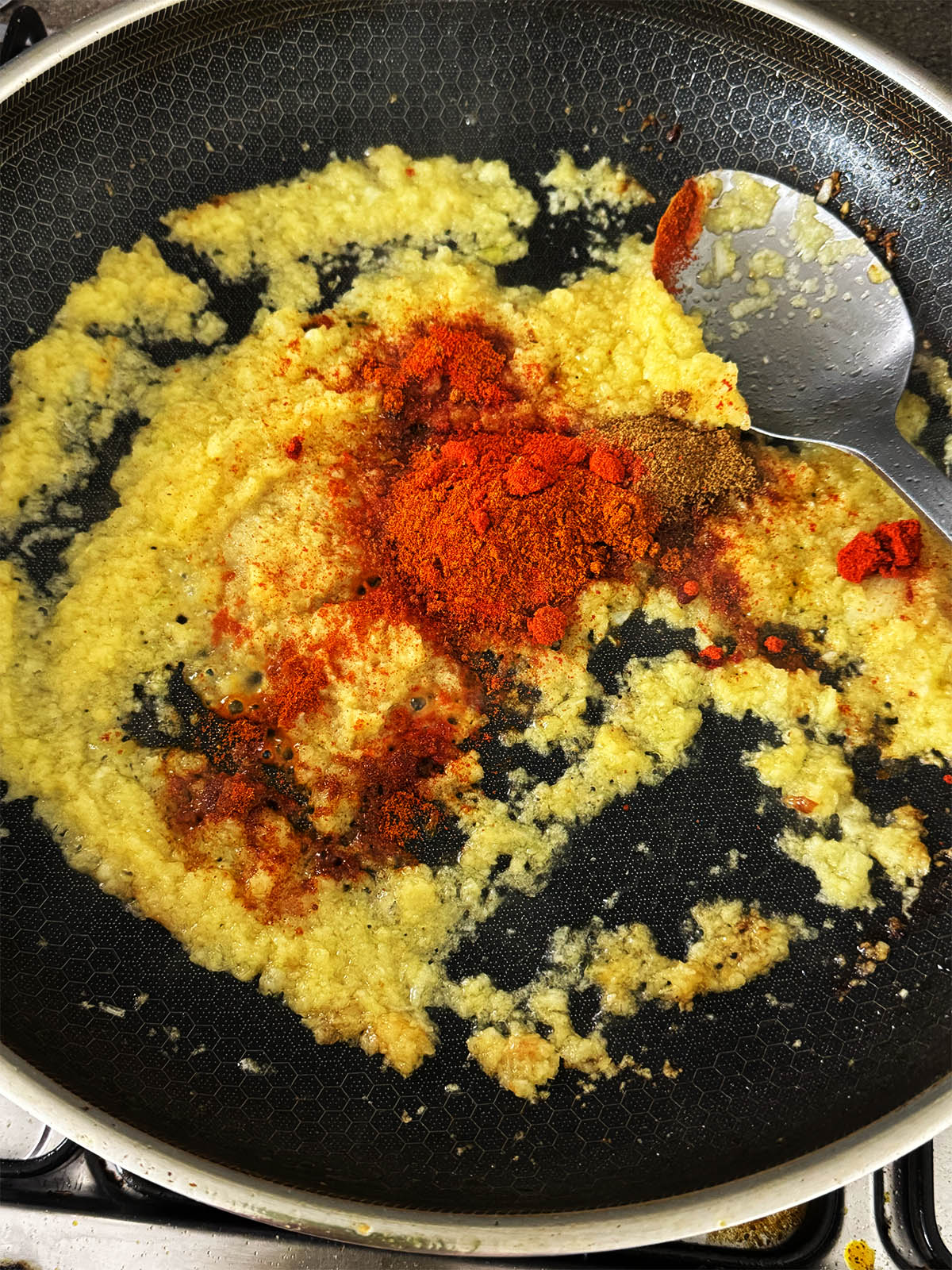 Adding the spices and garlic and ginger paste to the pan.