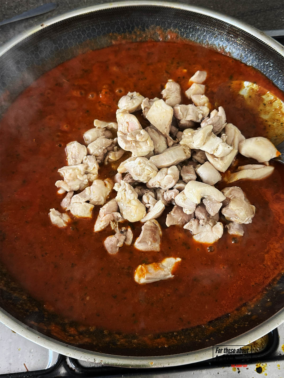 Adding the chicken to the sauce in the pan.