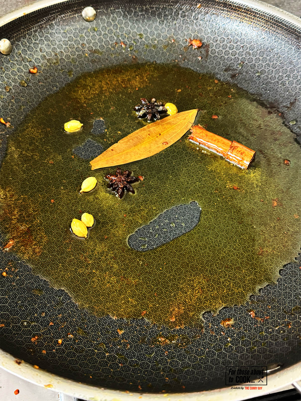 Infusing the whole spices in ghee in the pan.