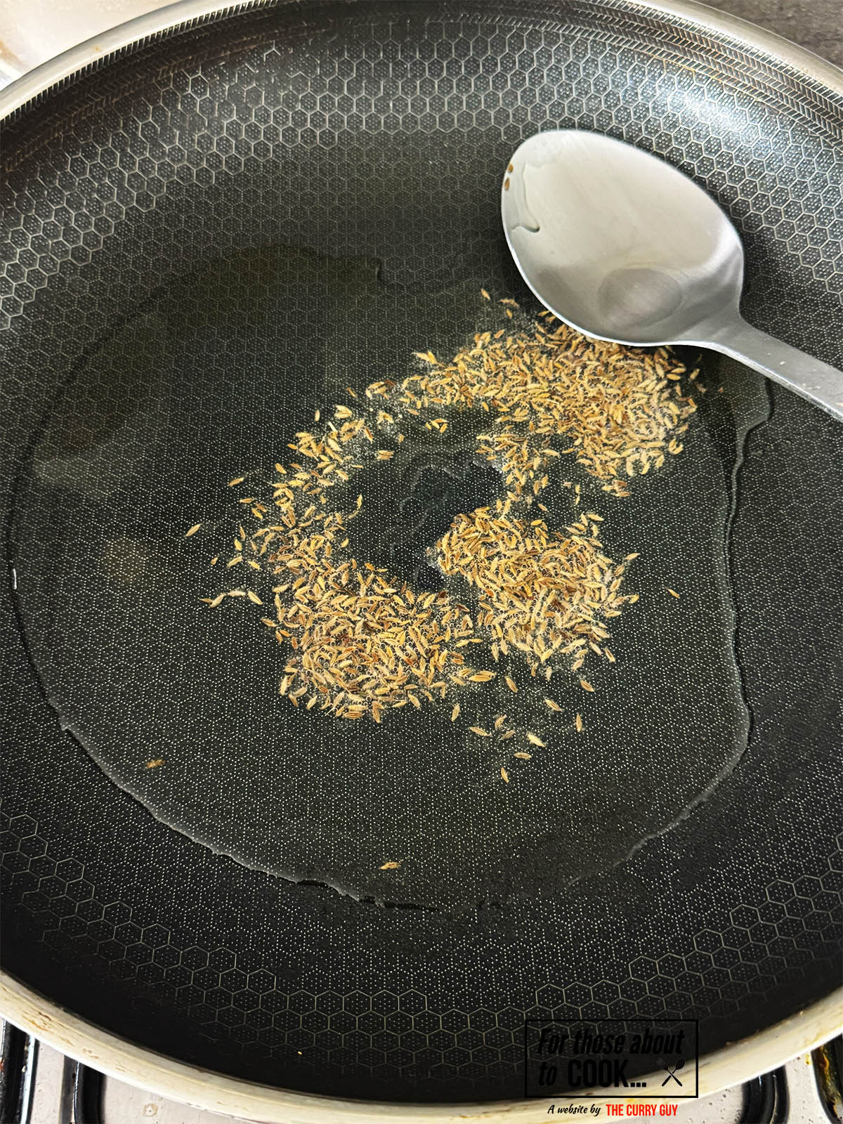 Infusing the cumin seeds into ghee in a hot pan.