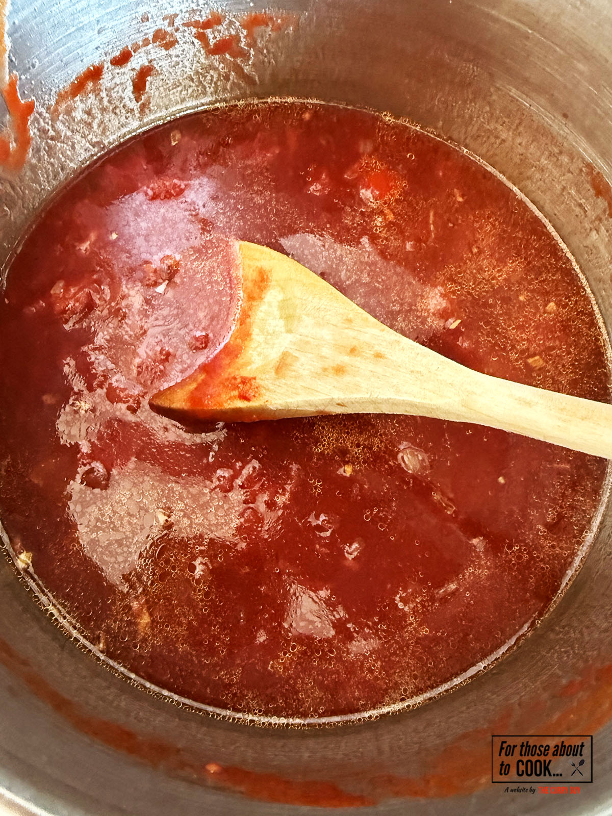Tomato sauce reducing in a pan with chicken stock and red wine
