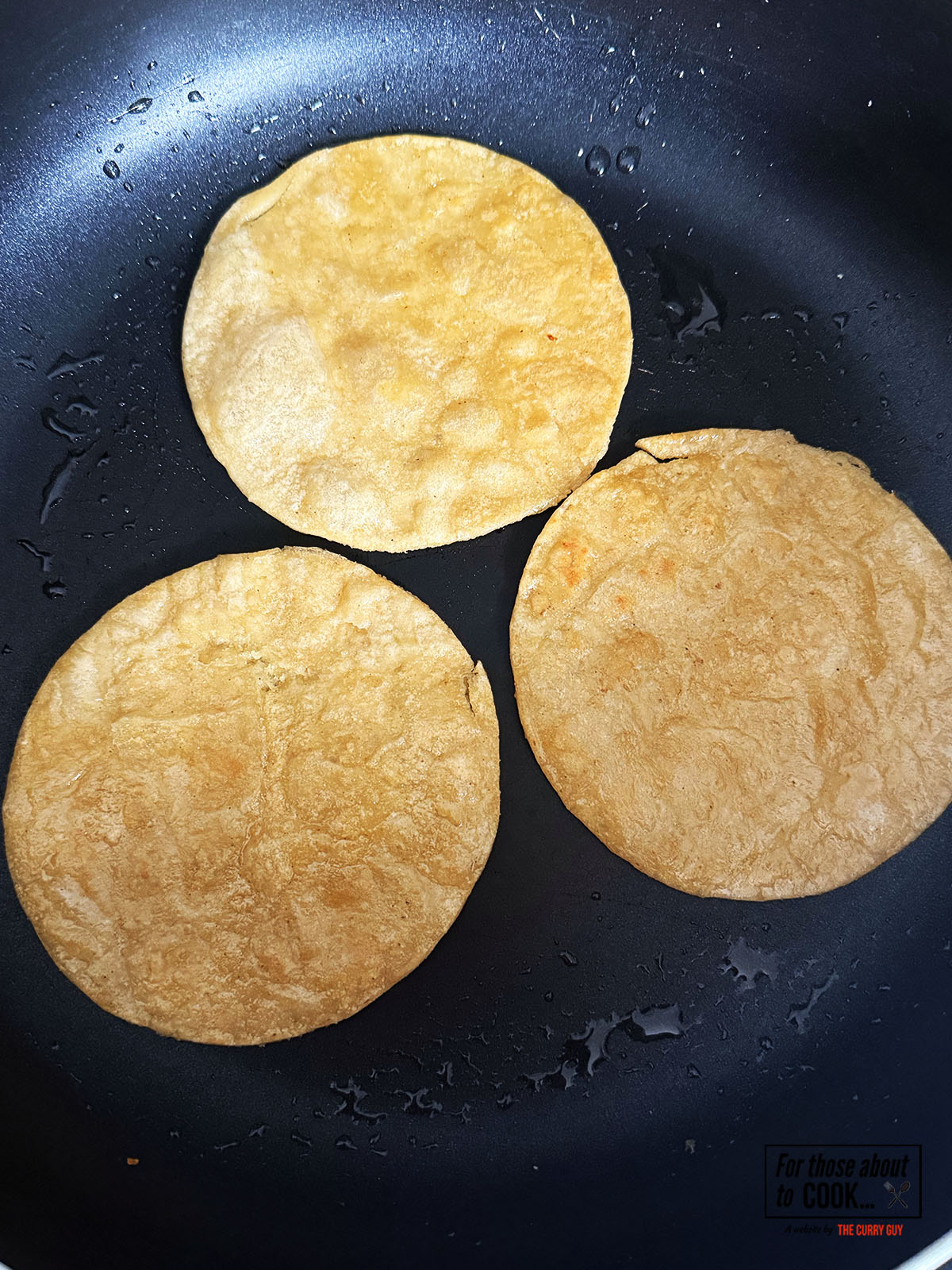 Corn tortillas crisping in a pan