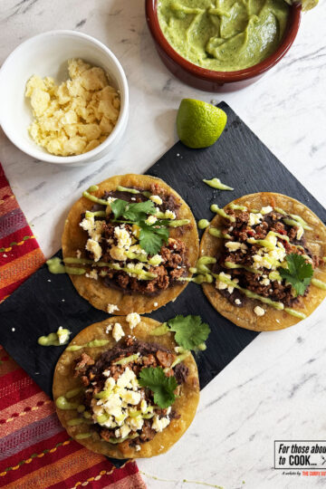 Finished tostadas topped with wensleydale cheese, coriander and salsa de aguacate