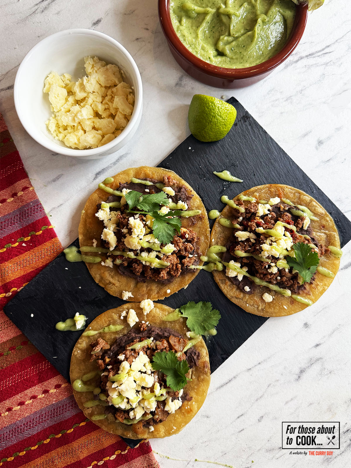 Finished tostadas topped with wensleydale cheese, coriander and salsa de aguacate