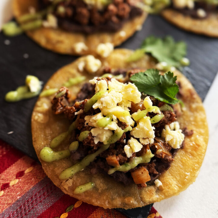 Beef tostadas topped with cheese and salsa de aguacate