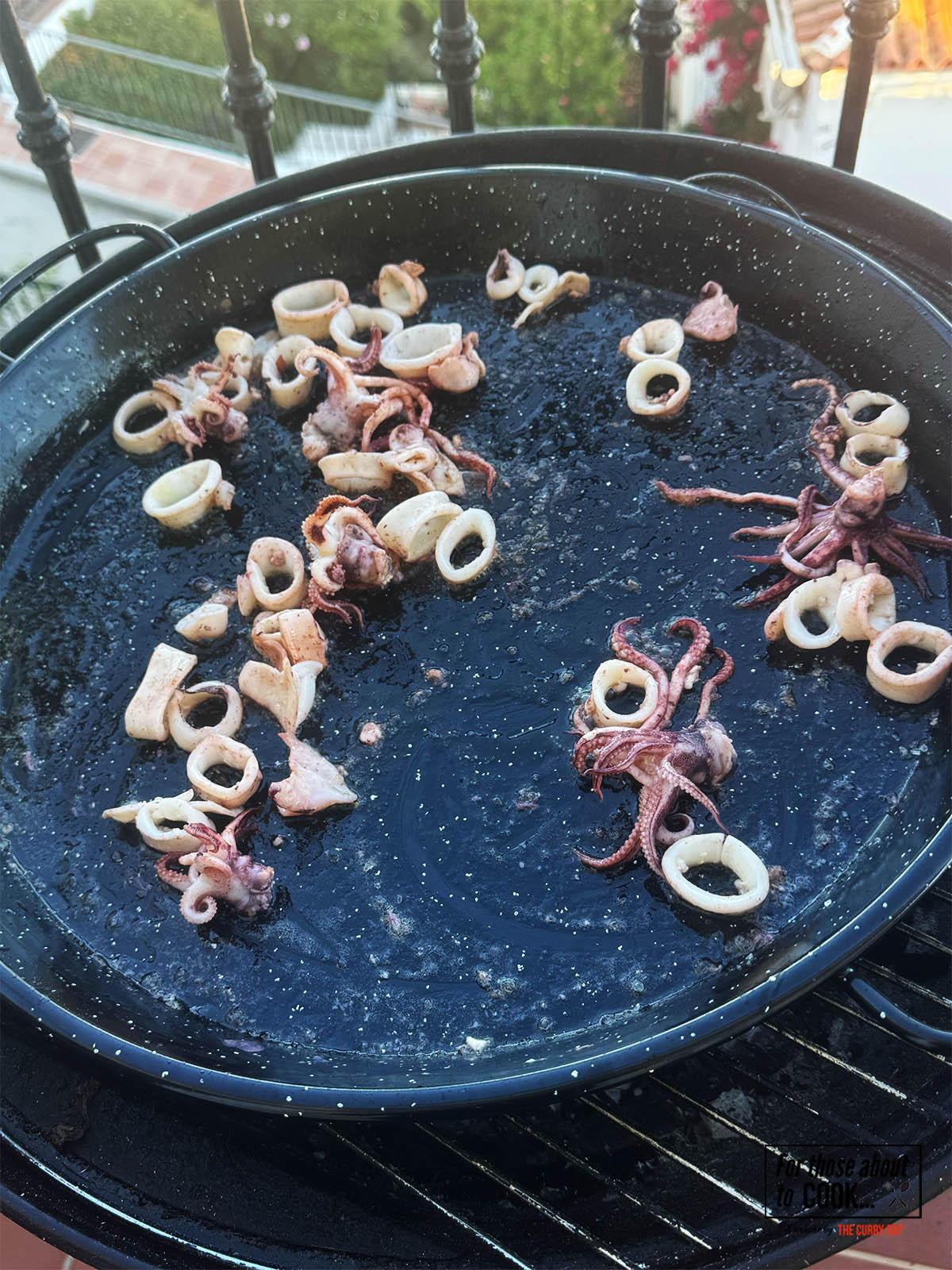 Frying squid over a medium-high heat in a paella pan.