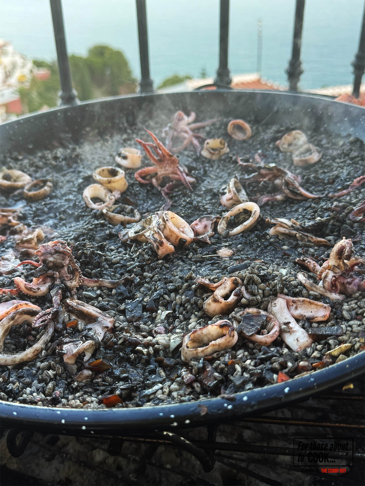 Returning the cooked squid to the black paella.