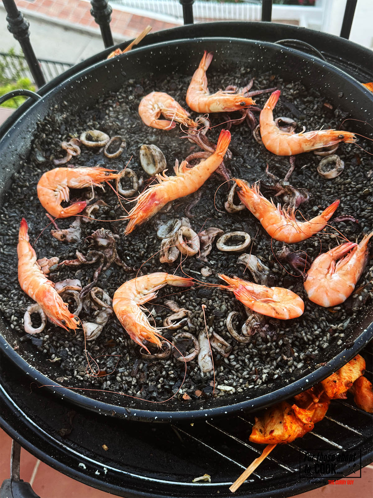 Adding cooked prawns to the paella before covering to rest for 5 minutes.