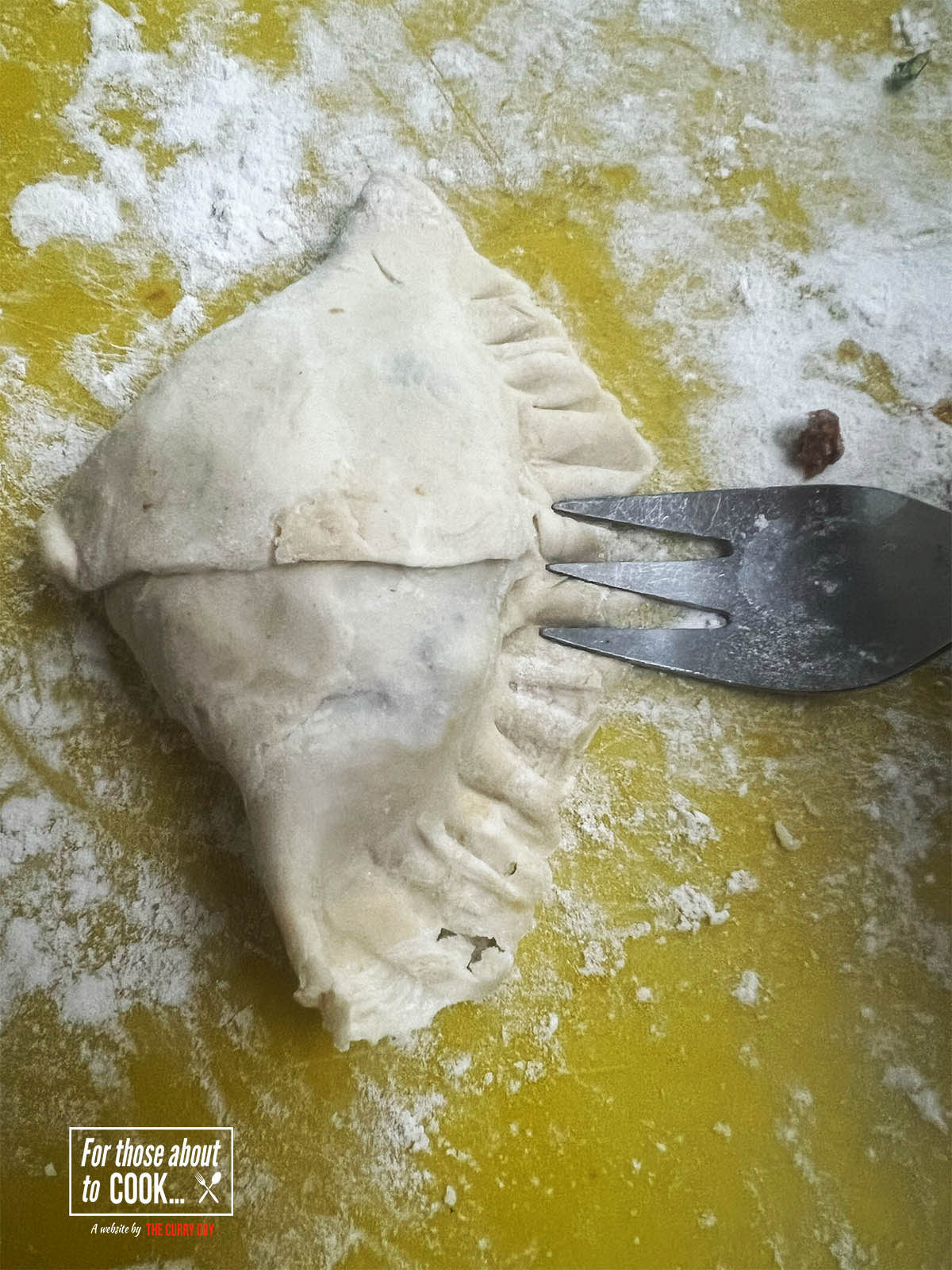 Using a fork to seal the samosa shut.