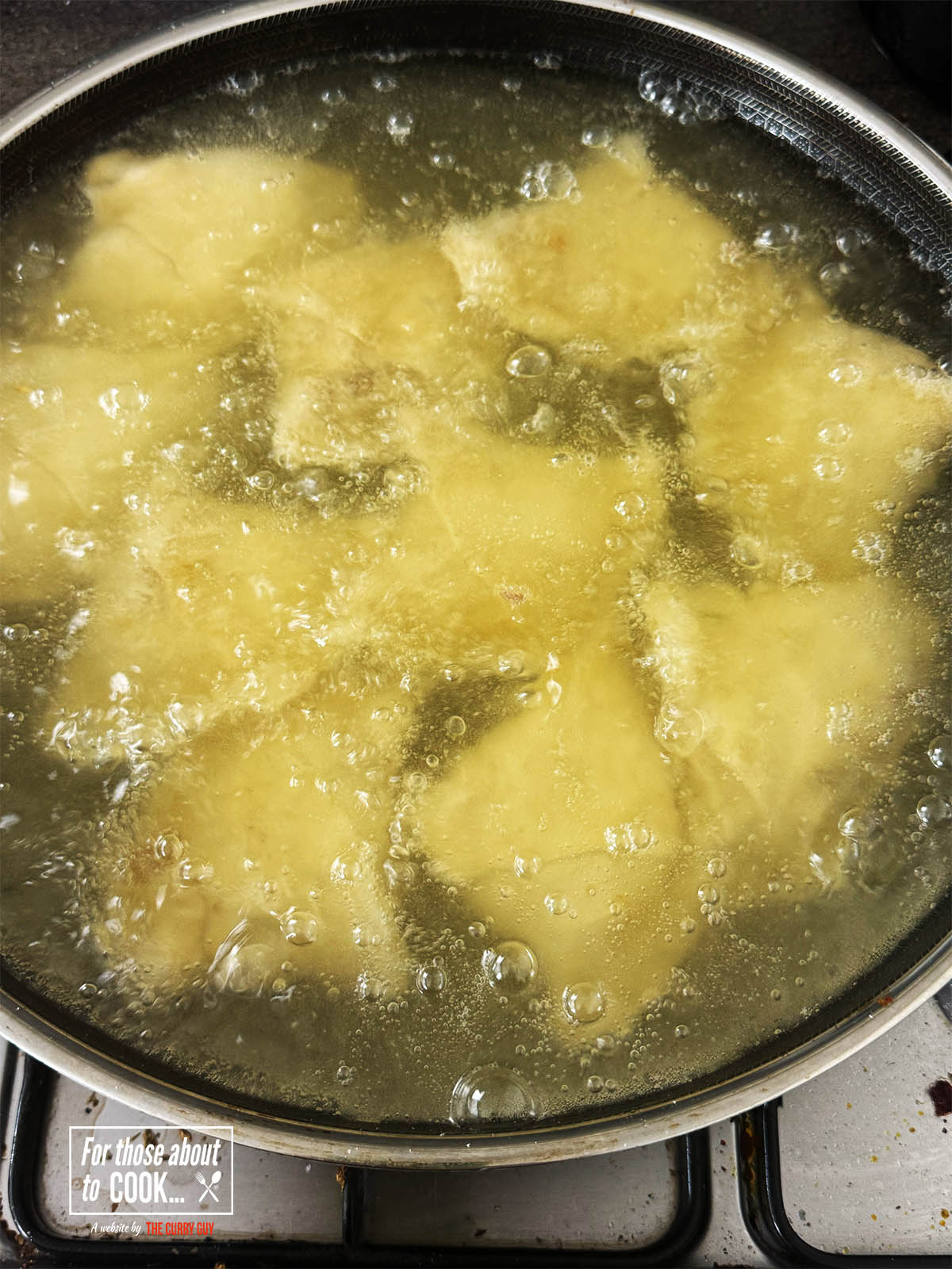 Adding the samosas to medium hot oil to fry for 8 minutes.
