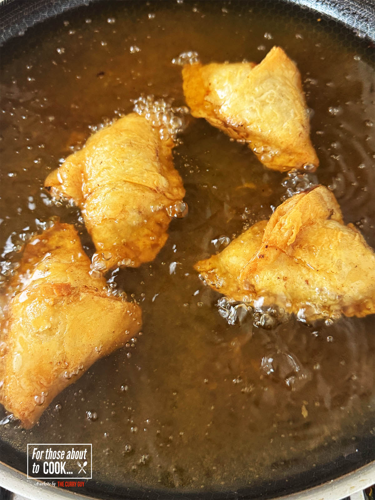 The finished samosas in the hot oil ready to transfer to a paper towel.
