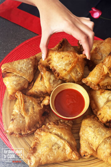 Hand reaching for one of the easy Keema Samosas