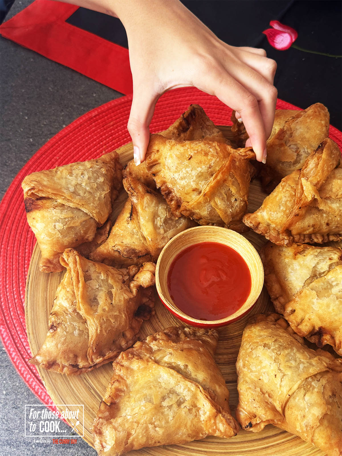 Hand reaching for one of the easy Keema Samosas