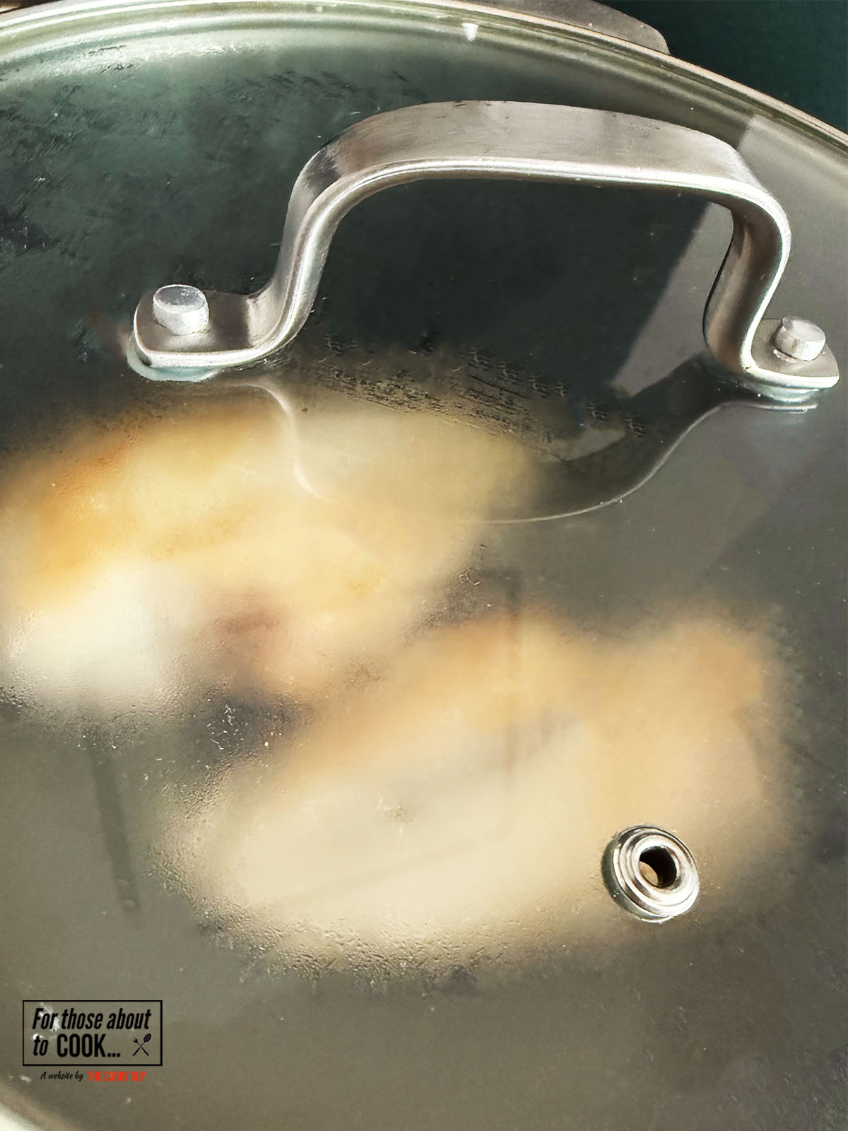 Lid covering pan with chicken and chicken stock inside