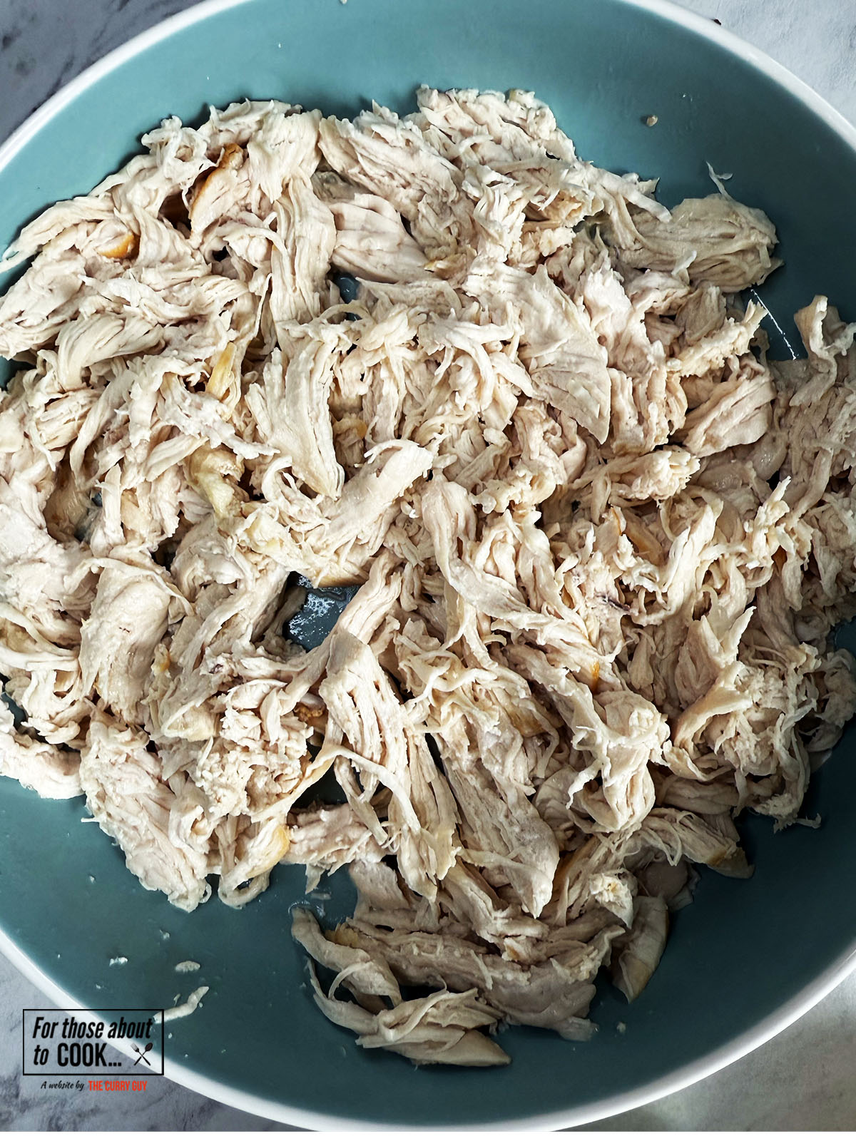 Poached chicken shredded in a bowl