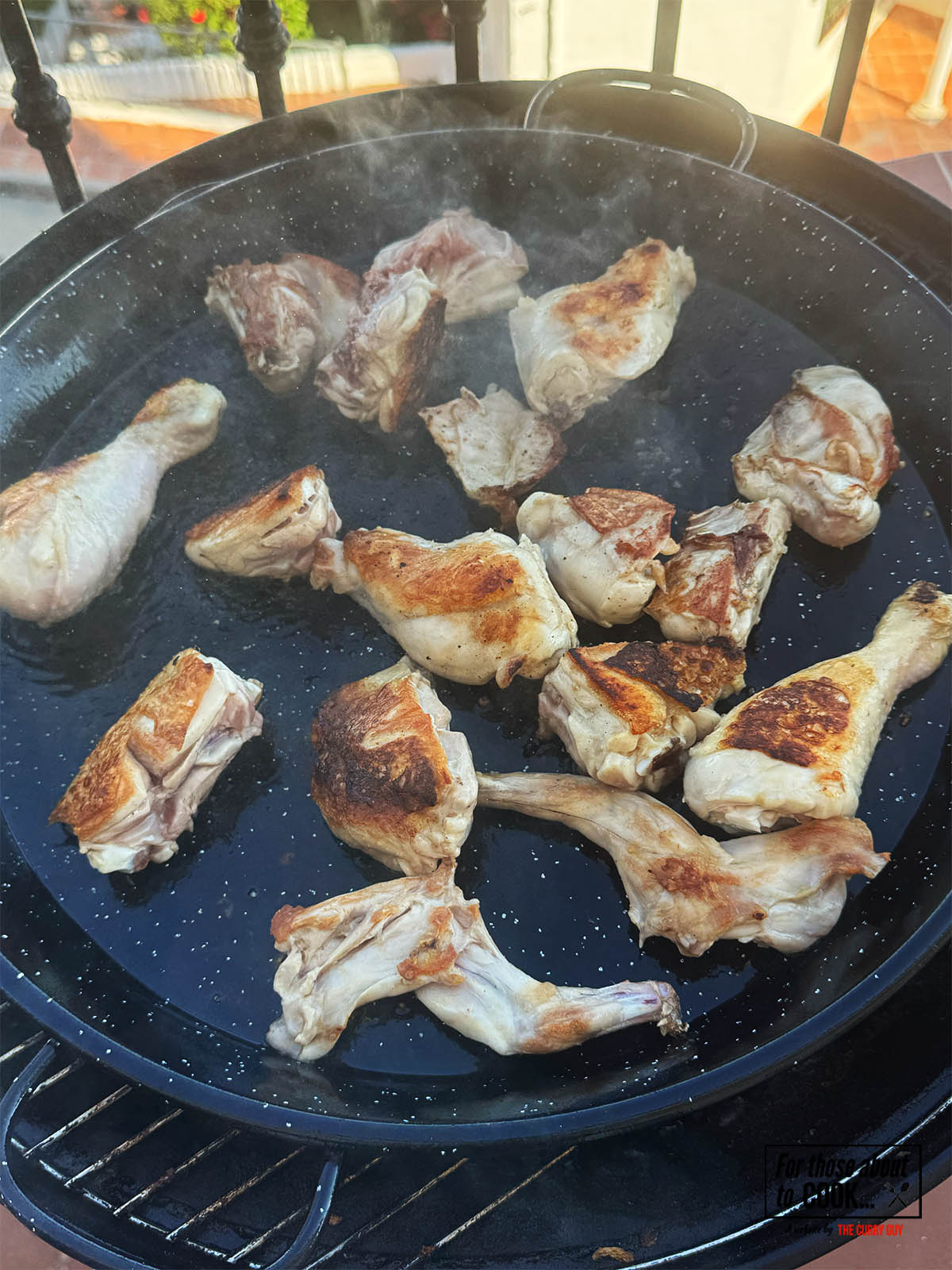 Frying the rabbit and chicken pieces in olive oil in a paella pan.