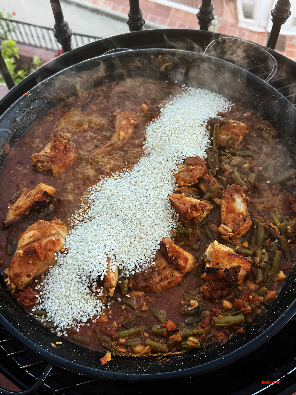 Adding the rice to the paella pan.