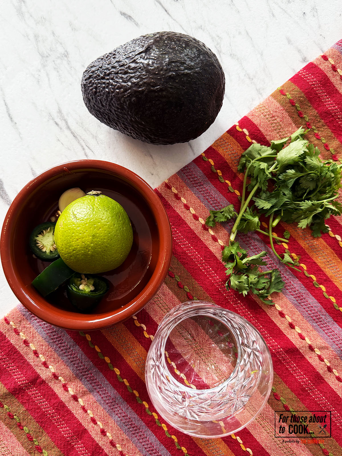 Avocado, coriander, garlic, lime juice and coriander separated into bowls.