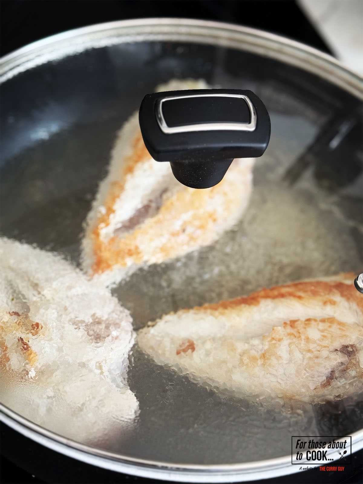 Lid covering pan with chicken and chicken stock