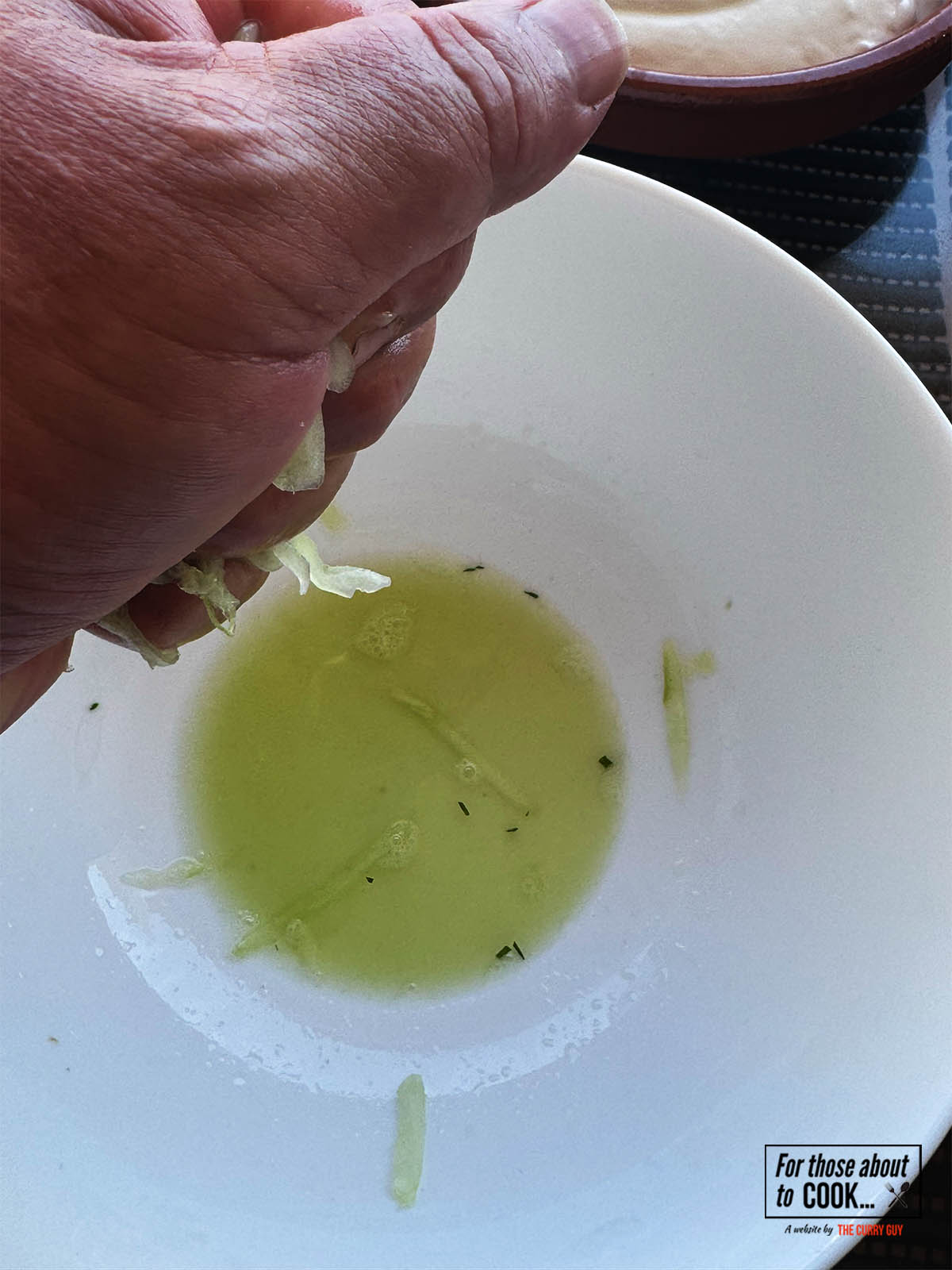 Squeezing the excess moisture from the grated cucumber.