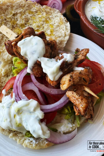 Chicken souvlaki served on a pita with crispy salad vegetables and tzatziki.