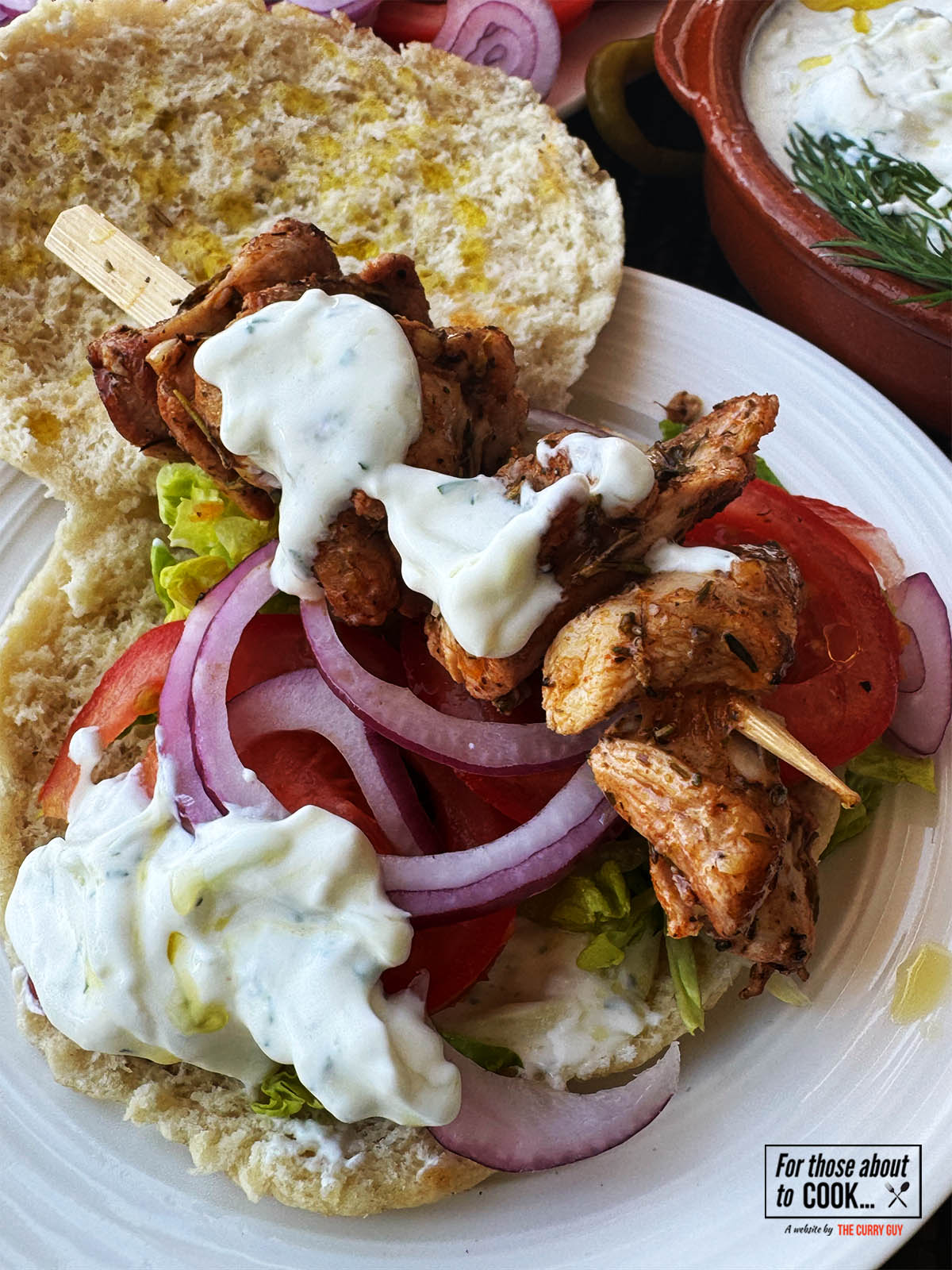 Chicken souvlaki served on a pita with crispy salad vegetables and tzatziki.