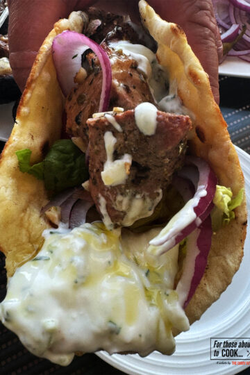 Pork souvlaki wrapped up in a pita with tzatziki and salad vegetables.